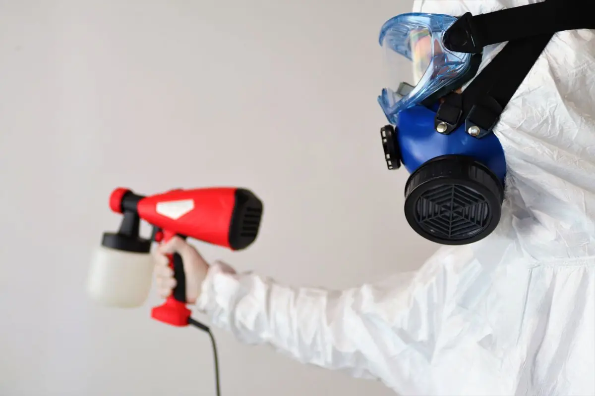 Technicien en équipement de protection réalisant une désinfection